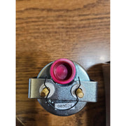 Mechanical component with pink and gold parts on a wooden surface